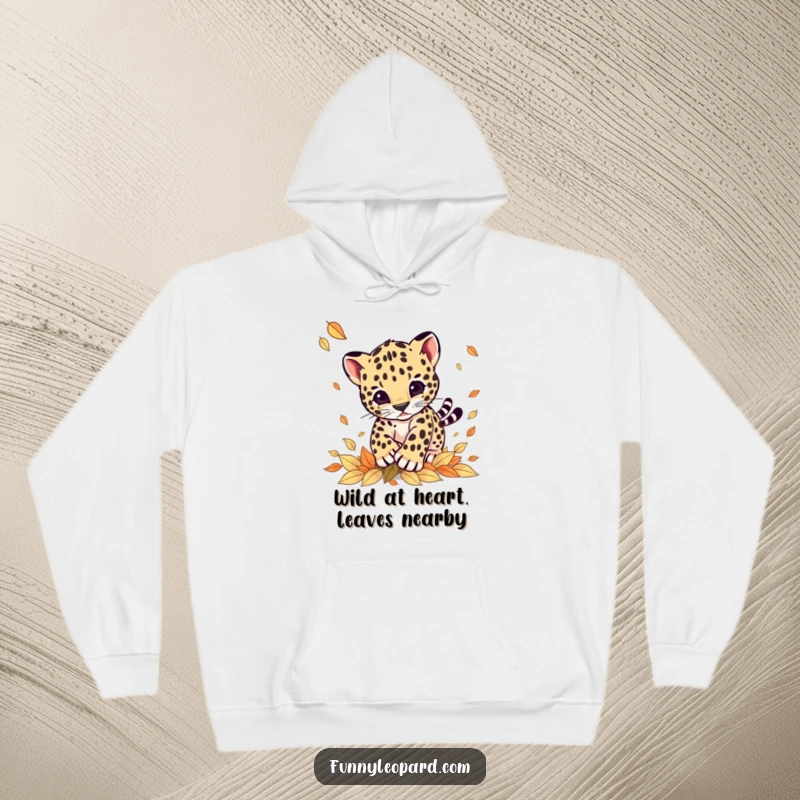 Funny hoodie showcasing an energetic leopard cub playfully pouncing on a scattering of autumn leaves, radiating warmth and cheer.